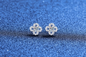 Macro shot of silver four-leaf clover moissanite stud earrings with pave diamond details