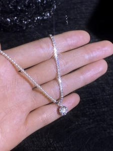 Close-up of S925 silver necklace with white pearls, pavé chain and moissanite pendant