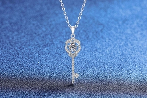 Macro detail of silver key pendant with sparkling round cut stone and pavé accents
