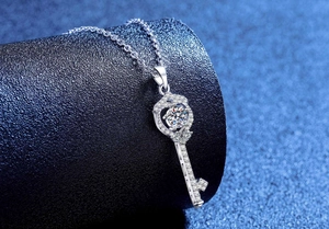 Detailed view of a silver key pendant set with a round moissanite on a dark starry background