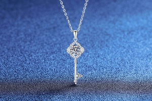 Macro detail of S925 silver key pendant necklace with moissanite stones on blue background