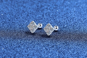 Macro shot of silver four-leaf clover moissanite earrings with screw-back on starry background
