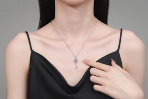 Close-up of a 925 sterling silver key necklace with a blue stone on a female model