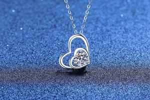 Macro shot of S925 silver double heart pendant with round moissanite on blue starry background