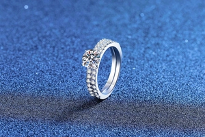 Macro view of a classic six-prong moissanite ring with double-row pavé diamond band