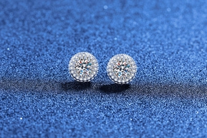 Macro shot of S925 sterling silver moissanite stud earrings on a dark blue glitter base