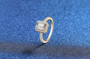 Nahaufnahme von Moissanit-Ring mit Radiant-Schliff und Halo auf blauem Glitzer