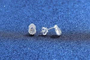 Detailed view of silver moissanite gourd earrings with butterfly backings on dark background