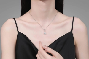 Gros plan d'un collier en argent S925 avec trois zircons et un pendentif perle blanche
