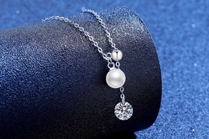 Detailed shot of S925 silver necklace with white pearl and sparkling moissanite pendant