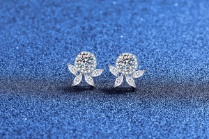 Macro shot of silver flower earrings with center stone and snowflake design on blue background