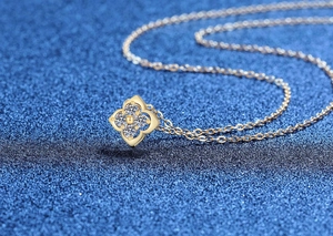 Macro detail of gold four-leaf clover necklace with sparkling white moissanite stones
