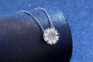 Macro shot of silver moissanite sunflower pendant on dark blue leather background
