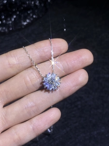 Macro shot of s925 sterling silver sunflower pendant with moissanite held in hand