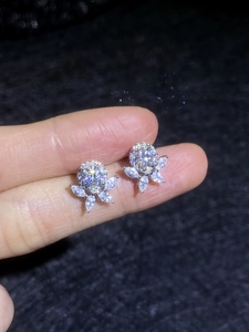 Macro shot of silver flower earrings with sparkling moissanite stones and petal design