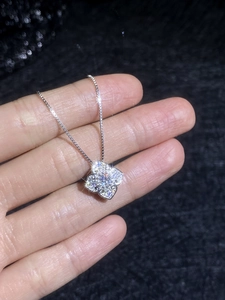 Macro shot of silver clover pendant necklace with sparkling pavé stones on black fabric