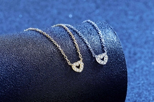 Dettaglio dei ciondoli a cuore traforato in oro e argento con pietre pavé luccicanti