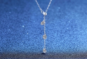 Gros plan d'un collier en argent S925 avec pendentif pompon et trois pierres moissanites