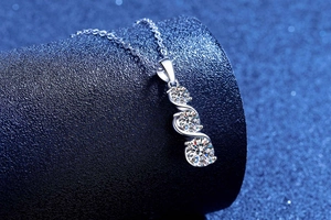 Close-up of S925 silver necklace with three moissanite stones on a blue display stand