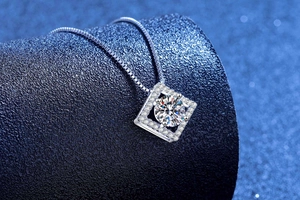 Macro di un ciondolo quadrato in argento con moissanite brillante su fondo blu