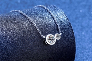 Detail of silver S925 moissanite bubble pendant on refined cross chain with blue backdrop