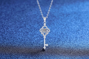 Macro shot of silver clover key pendant with sparkling round center stone and cross chain
