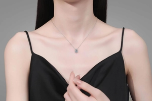 Gros plan d'un collier gourde en argent avec moissanite bleue sur un mannequin
