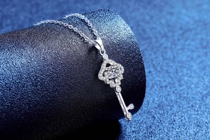 Detailed side view of silver key pendant with four-leaf clover design and sparkling stone
