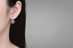 Close-up of S925 silver flower earrings with blue gems and cubic zirconia on a model