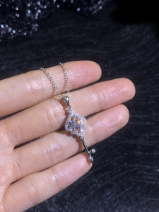 Macro shot of silver key pendant with brilliant cut center stone and micro-pave diamonds