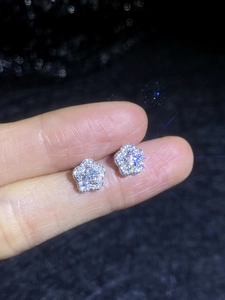 Macro shot of S925 sterling silver plum blossom moissanite stud earrings held by hand