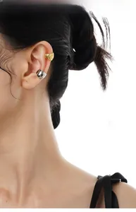 Dettaglio di un set di ear cuff minimalisti oro e argento indossati da una modella