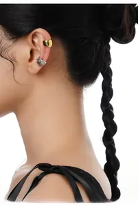 Dettaglio di ear cuff oro e argento con trama lava indossati sull'orecchio