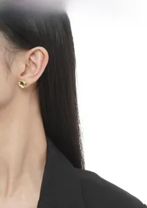 Model wearing minimalist gold heart stud earrings in polished sterling silver finish