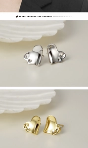 Detailed view of silver and gold heart earrings with unique circular indentations