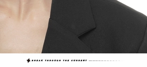 Detail view of lapel tailoring and twill texture on a black tailored blazer for women