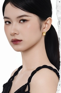 Close-up of golden oval stud earrings with white freshwater pearls on a model's ear