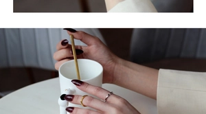Detailaufnahme von minimalistischen dünnen Ringen in Gold und Silber beim Teetrinken