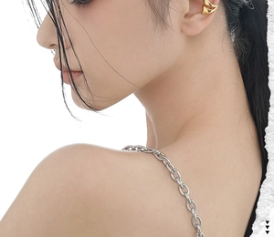 Detail of a minimalist gold double-layer ear cuff worn with a thick silver metal chain