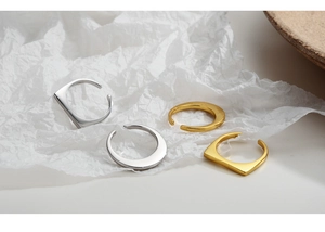 Dettaglio di anelli geometrici in argento S925 e oro su carta bianca testurizzata fine