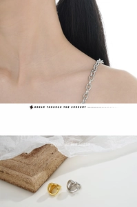 Macro detail of minimalist double-layered silver ear cuffs and chunky industrial chain