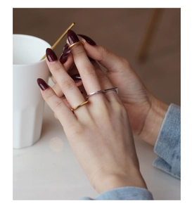 Vista macro di anelli minimalisti in oro e argento indossati sovrapposti in un caffè