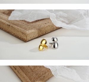 Minimalist polished gold and silver drop ear cuffs shown on a minimalist white backdrop