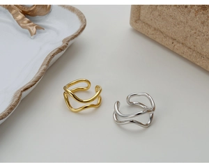 Macro detail of S925 hallmark on minimalist wavy silver and gold layered rings
