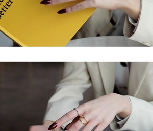 Detail of stacked S925 sterling silver Mobius rings worn on a hand over yellow books