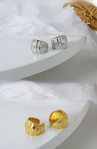 Dettaglio macro di orecchini a clip in argento S925 con trama lava e marchio