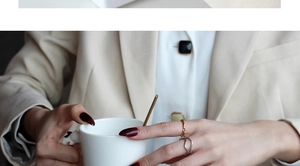 Detail of layered S925 silver wave and gold twist rings on model holding a cup