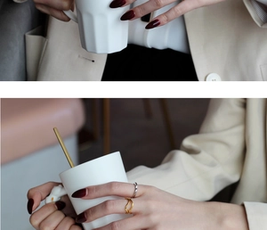 Detailed shot of gold and silver irregular wavy rings worn by a model holding a cup