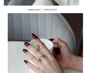 Close-up of wavy double-layer S925 silver and gold rings on hand holding a white cup