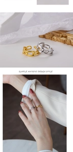 Detail of s925 silver and gold chain rings worn on fingers in a minimalist style